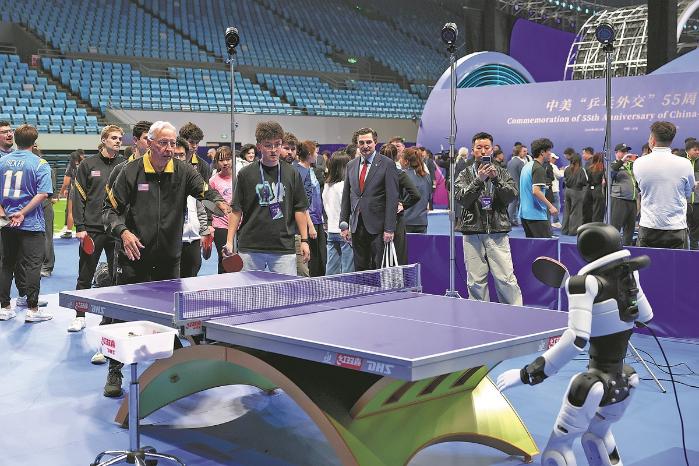 Guests play table tennis against a robot at an event to commemorate the 55th anniversary of Ping-Pong Diplomacy in Beijing on April 10. The event also marked the launch of sports exchange activities between Chinese and United States youth. WANG ZHUANGFEI/CHINA DAILY