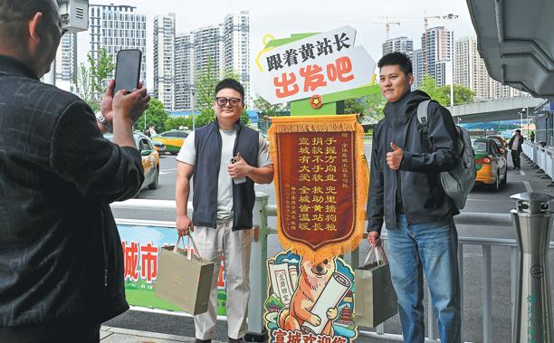 Visiting tourists pose with a cardboard image of Chief Huang at the station on Friday. (Photo: Wen Qin/ China Daily)