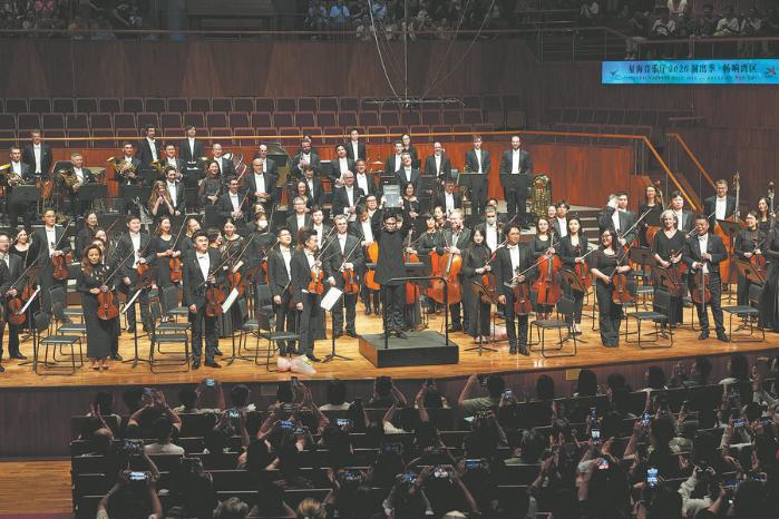Peltokoski (front) holds up the conductor's score of Shostakovich's Symphony No 11 in G Minor during the curtain call. (Photo: Desmond Chan/ China Daily)