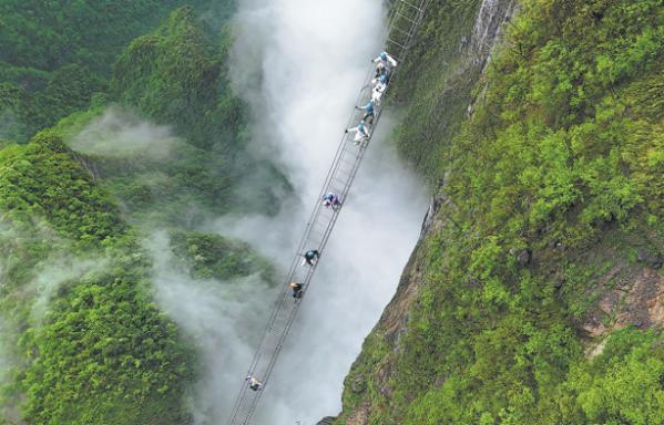Visitors take on the 168-meter "sky ladder", which is part of a protected climbing route on Qixing Mountain in Zhangjiajie, Hunan province, in April. (Photo: China Daily)