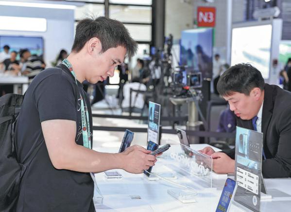 Visitors try out foldable smartphones at an exhibition in Shanghai on June 25. (Photo: China Daily)