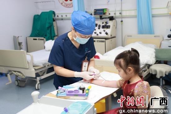 图为医护人员为妮娜进行抽血检查。何梦莹 摄